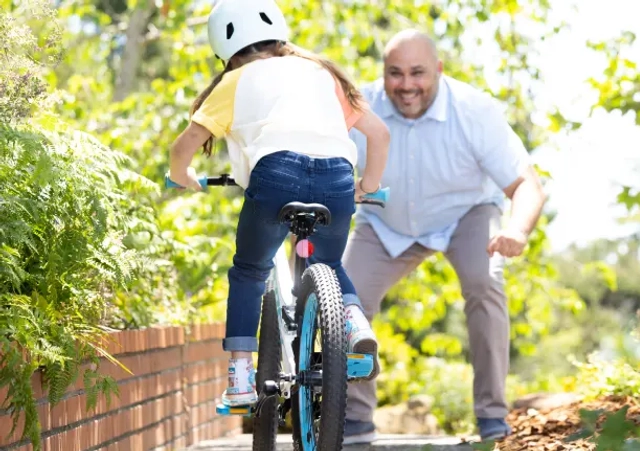 man teaching young girl to ride a bicycle